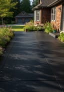 Near-black broom-finish poured concrete patio, cedar-clad home, bistro table, morning light