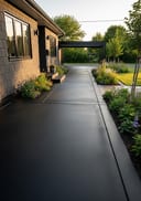 Near-black polished poured concrete courtyard patio, grey fibre cement bungalow, golden hour