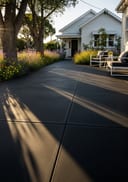 Near-black broom poured concrete front patio, white weatherboard cottage, long afternoon shadows