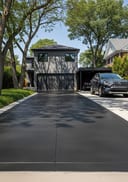 Near-black raw poured concrete driveway, grey fibre cement bungalow, Toyota RAV4, midday sun