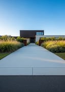 Light grey polished poured concrete front path, Corten steel and render home, clear morning sun