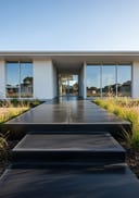 Charcoal polished poured concrete entry porch, white flat-roof home with floor-to-ceiling glazing, morning