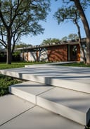 Light grey polished poured concrete front stoop, flat-roof concrete-and-timber home, morning sun