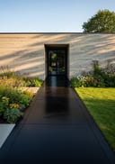 Near-black polished poured concrete side path, minimalist board-formed home, late afternoon