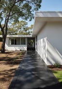 Near-black polished poured concrete side path, white flat-roof home with glazing, oblique angle, afternoon