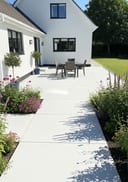 Light grey lightly polished poured concrete patio, single-storey white rendered bungalow with dark wi, bright sunny afternoon, crisp hard shado